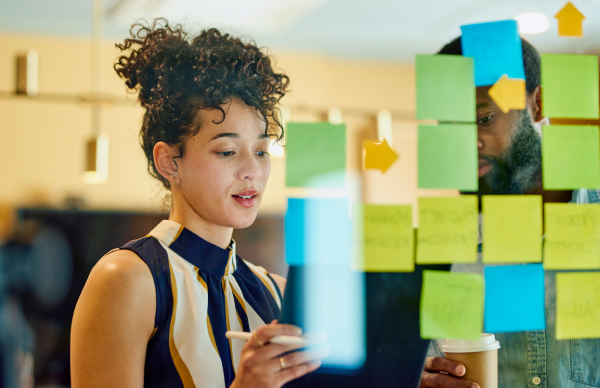 Advantages of working at Voltaira – Development opportunities Woman sticking post-it notes onto a glass board